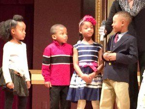 A group of children standing next to each other on a stage