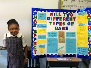 A young girl stands in front of a bulletin board that says will two different types of bags