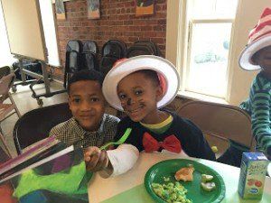 Two young boys are sitting at a table with plates of food.