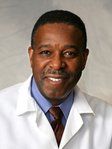 A man in a white coat and tie is smiling for the camera.