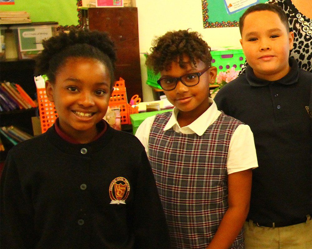 Three children are posing for a picture in a classroom