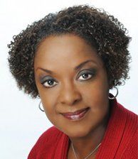 A woman with curly hair is wearing a red shirt and earrings.