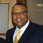 A man in a suit and tie is smiling for the camera.