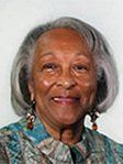 A woman with gray hair and earrings is smiling for the camera.