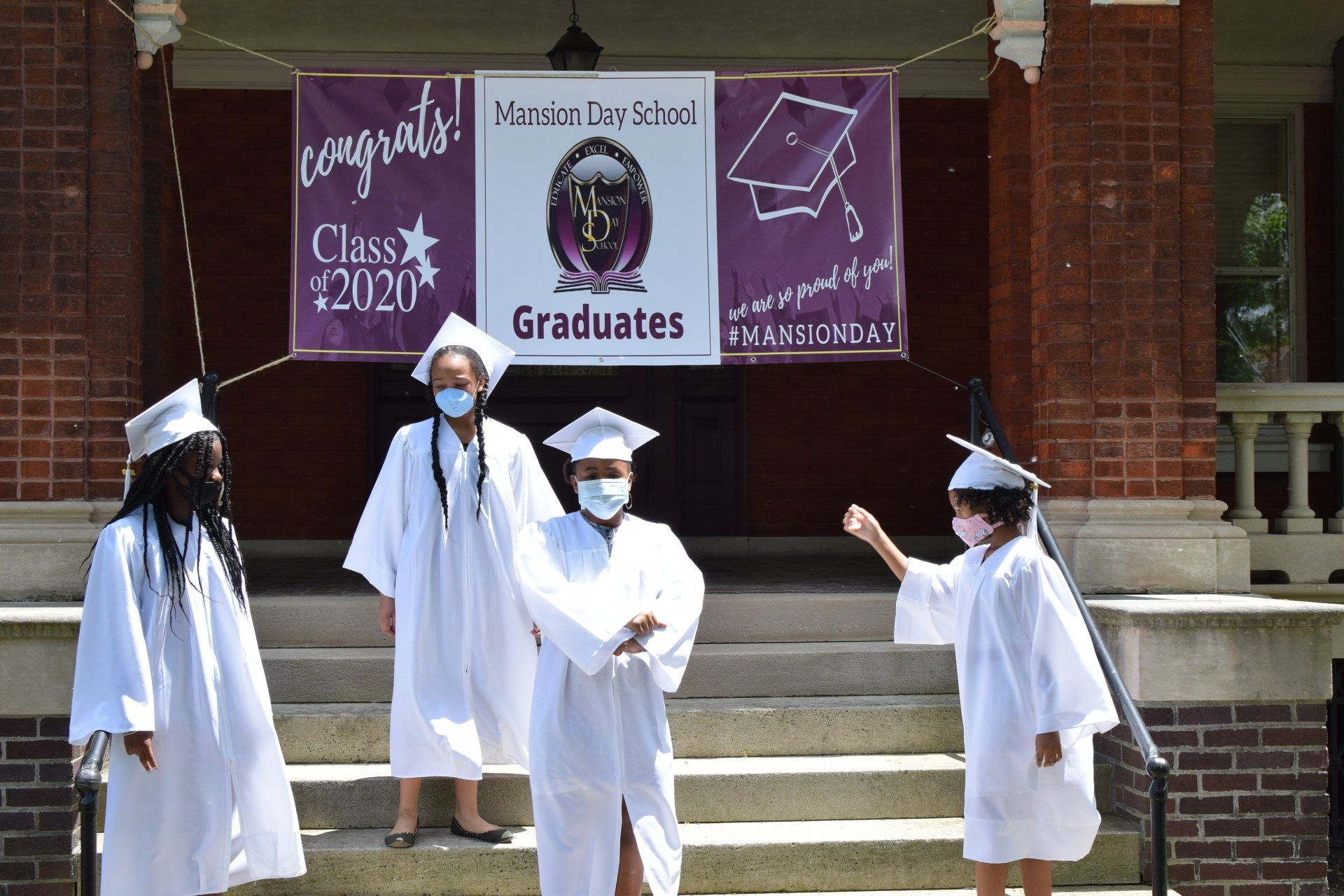 A group of graduates are standing in front of a sign that says congratulations class of 2020 graduates