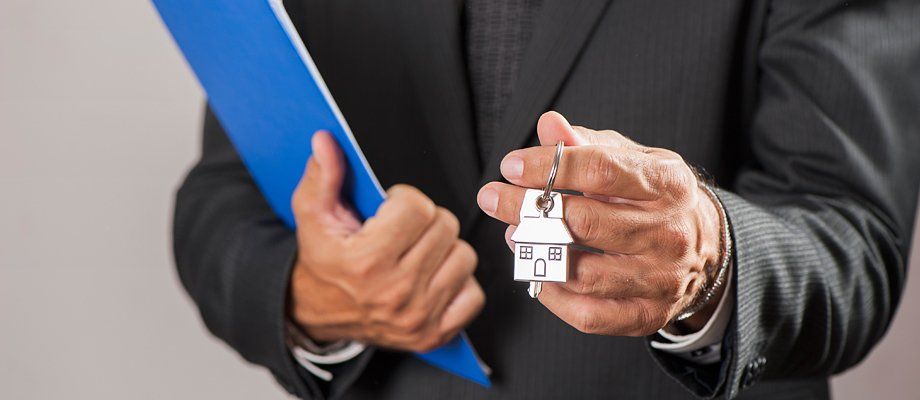 A man holding a set of keys with a house keyring