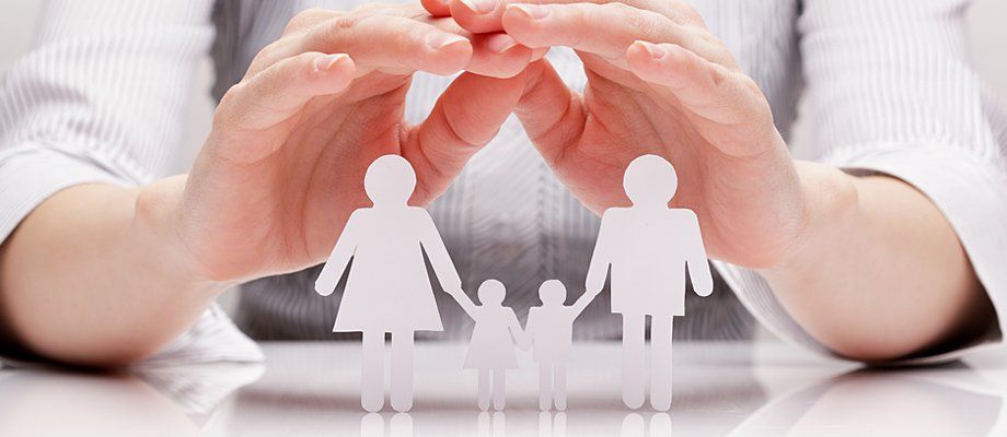 A pair of hands cupped over a family thats been cut out of paper