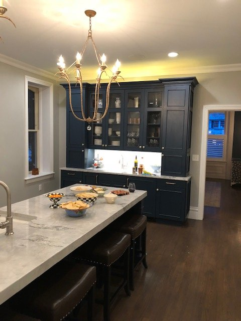 A kitchen with blue cabinets and a marble counter top