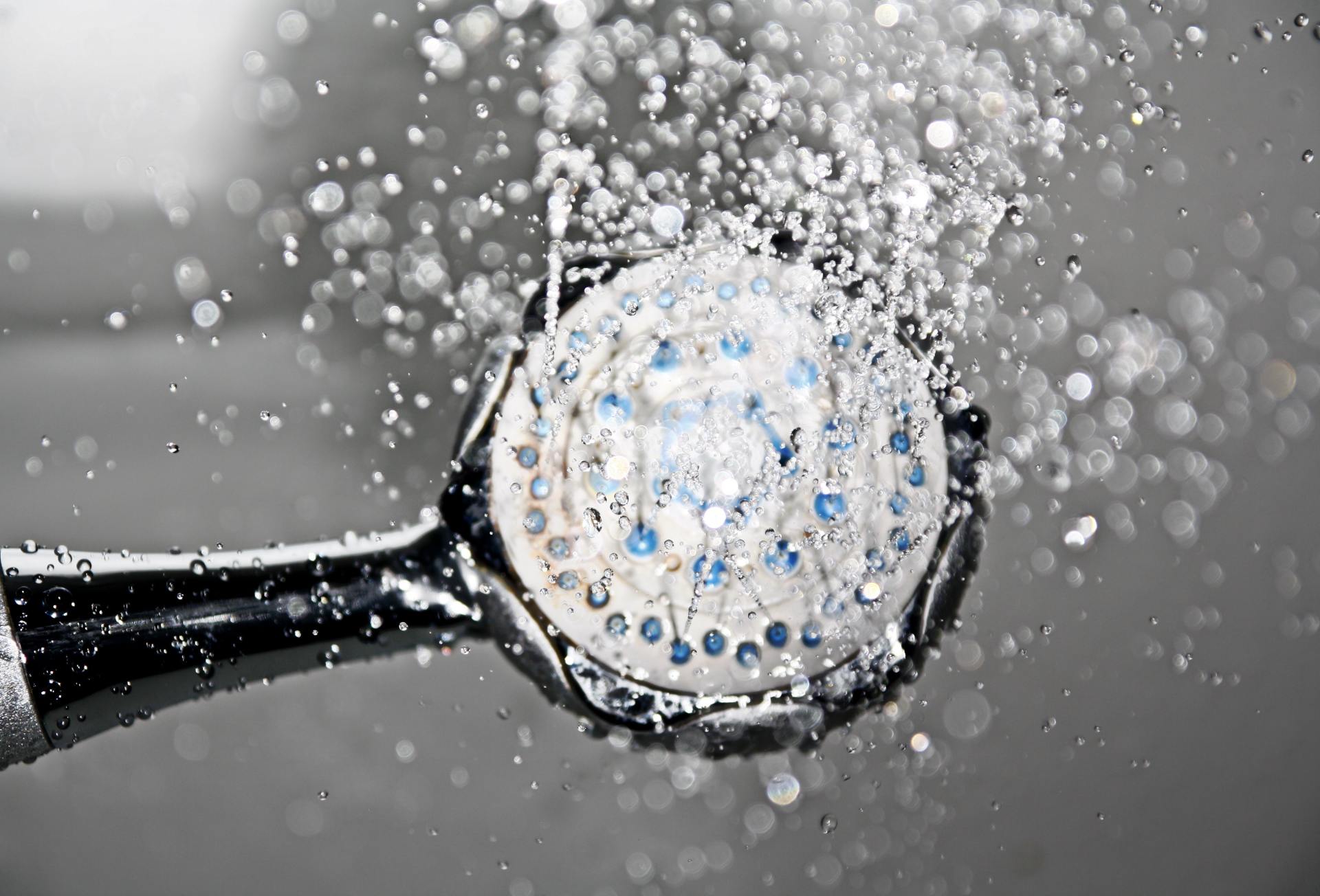 A close up of a shower head with water splashing out of it