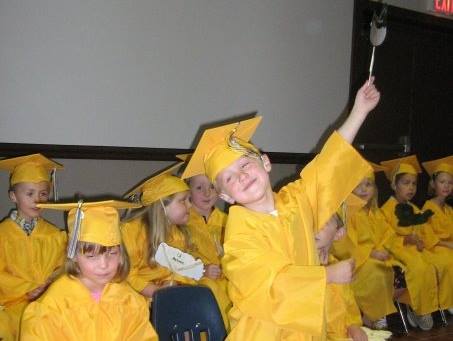 A group of children wearing yellow graduation caps and gowns
