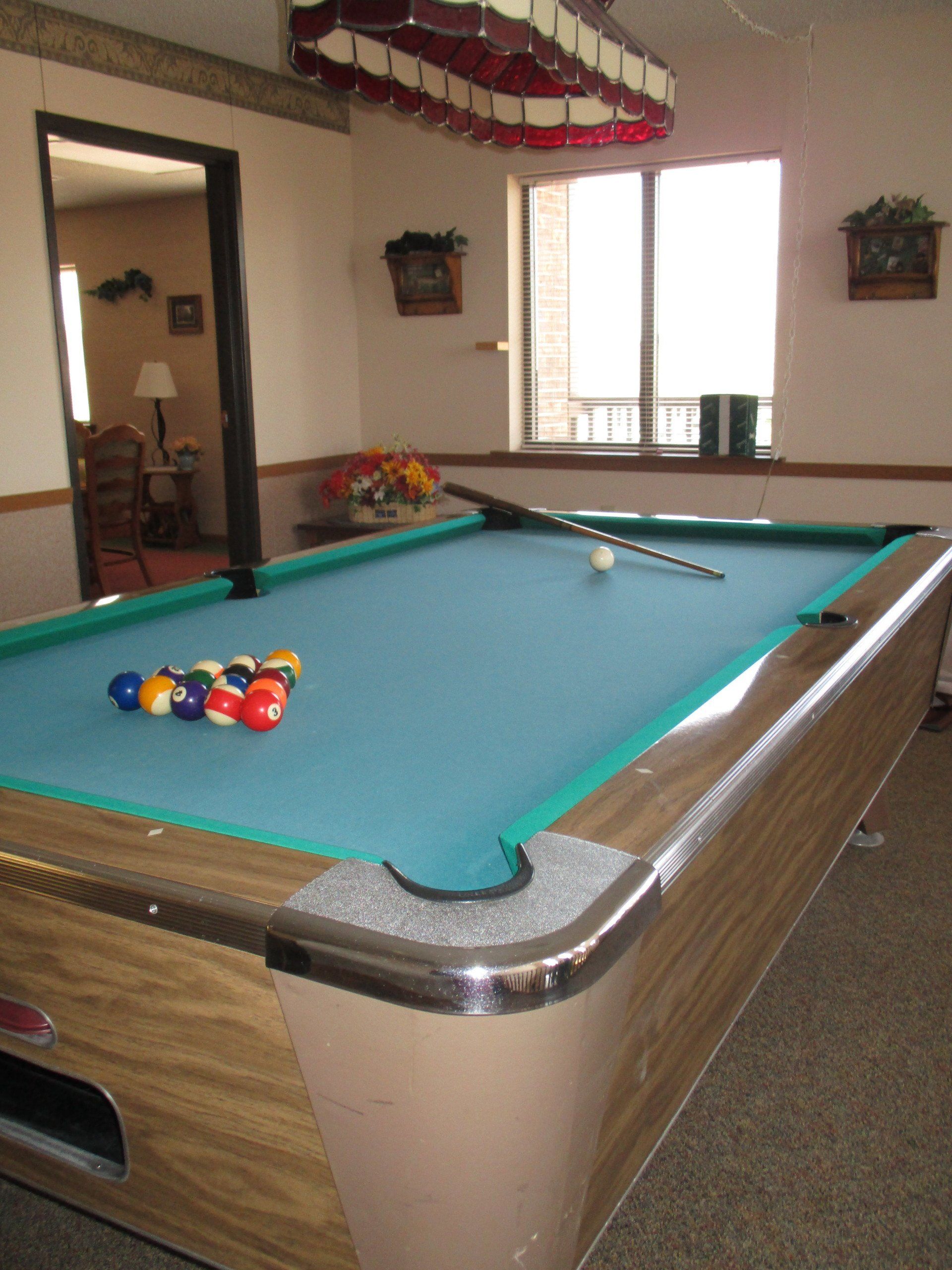 A pool table with balls and a cue on it