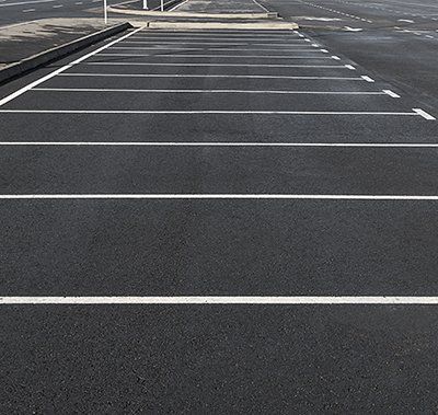Parking Lots Pavement — Worker Holding A Shovel With Paving Machine In Kent, WA Parking Lots Pavement — Worker Holding A Shovel With Paving Machine In Kent, WA