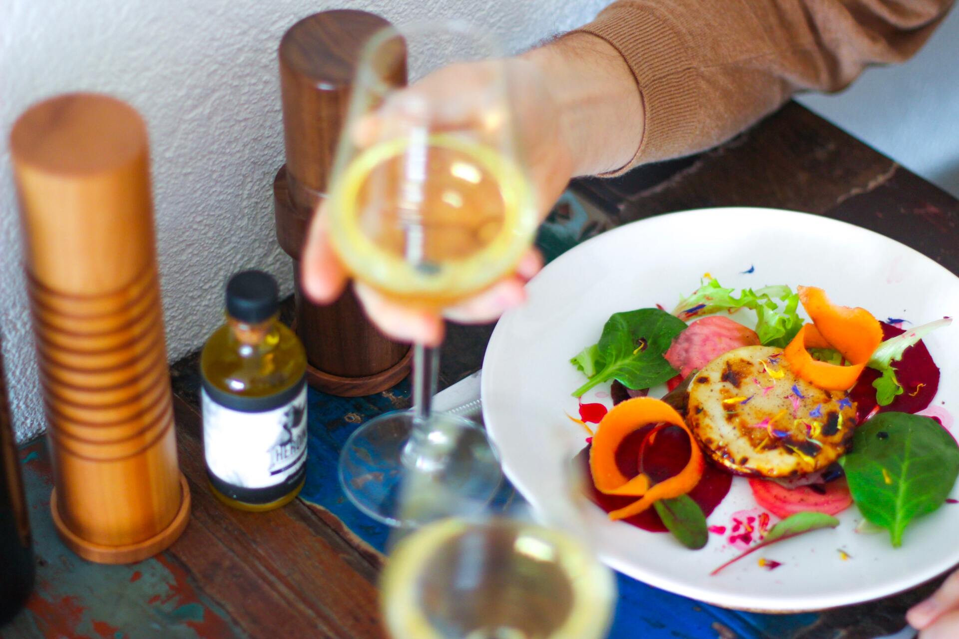 Plated gourmet salad with wine glasses and a bottle on a restaurant table