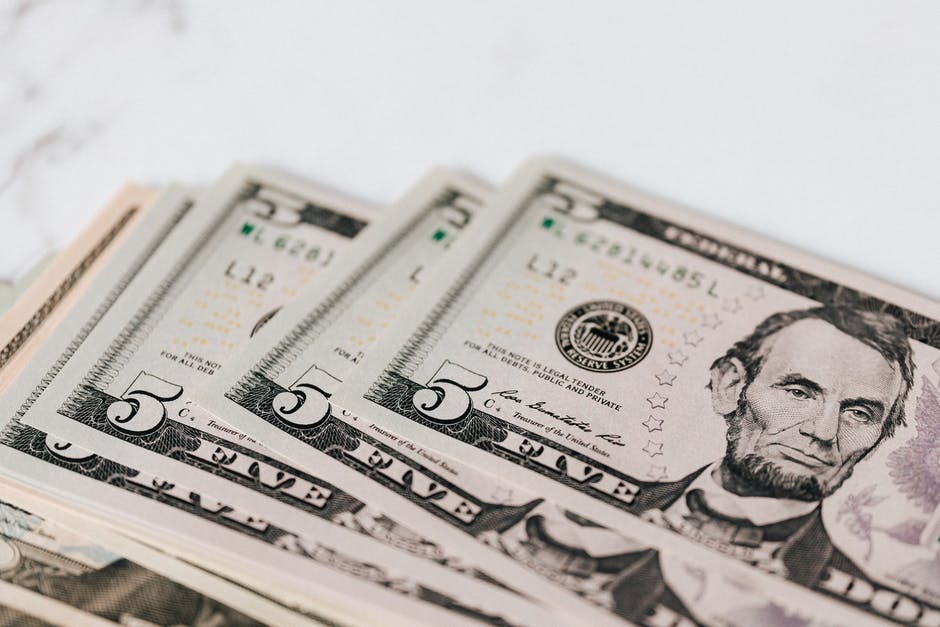 Stack of U.S. five-dollar bills fanned out, with Abraham Lincoln visible on the top bill.