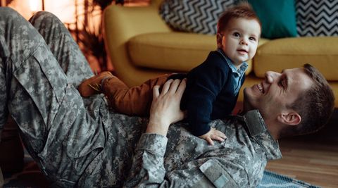 A father and his young son play together in the living room