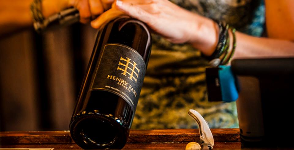 A woman is holding a bottle of wine on a counter.