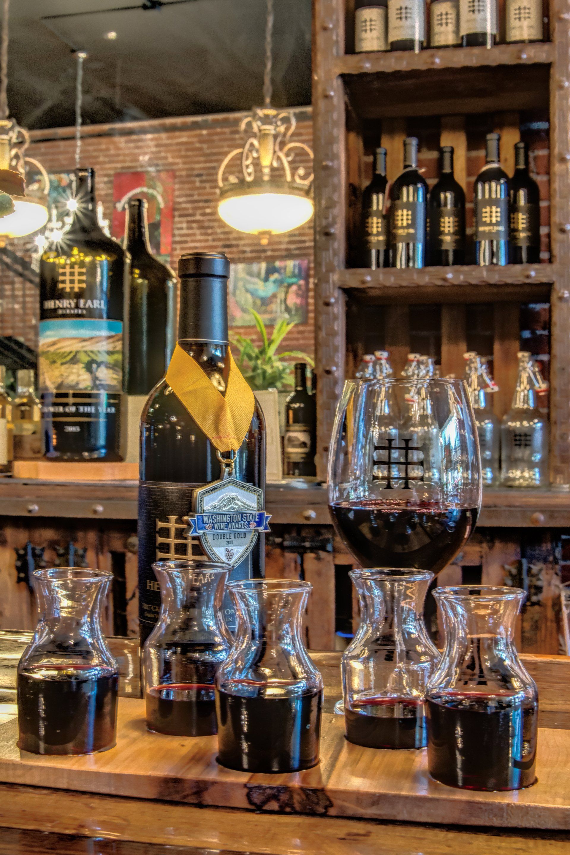 A bottle of wine is sitting on a wooden table next to a glass of wine.