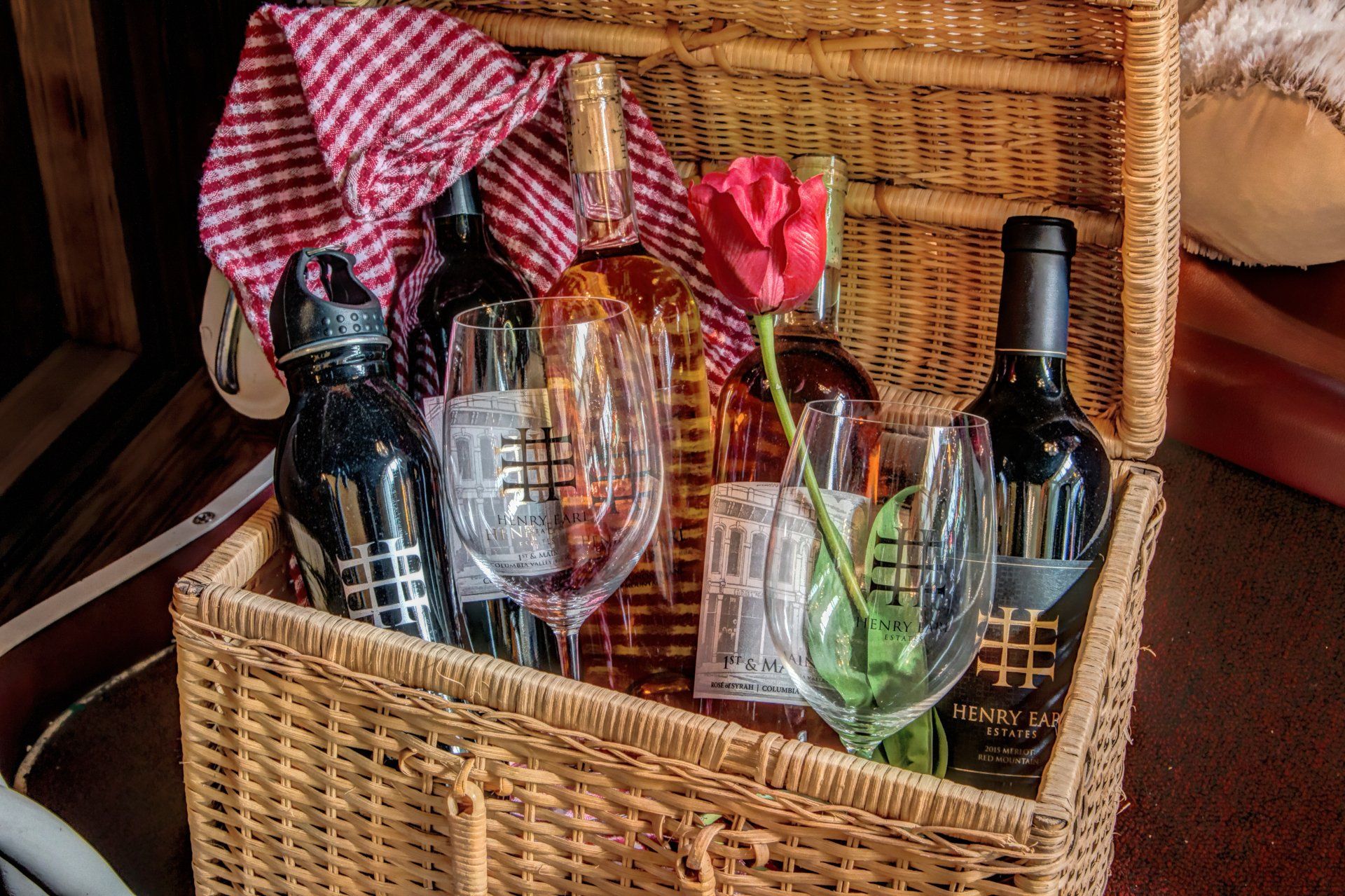 A wicker basket filled with wine bottles and glasses