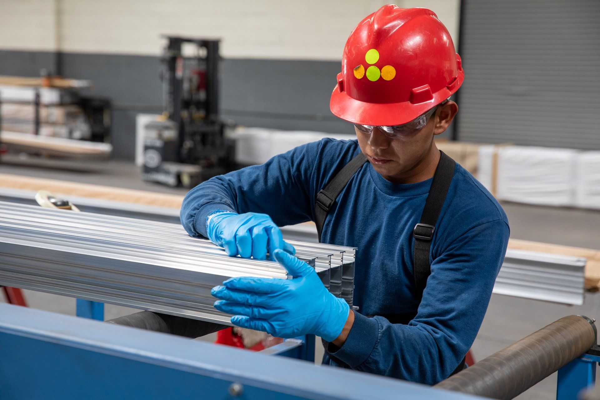 man with red hard hat fixing long pieces of metal