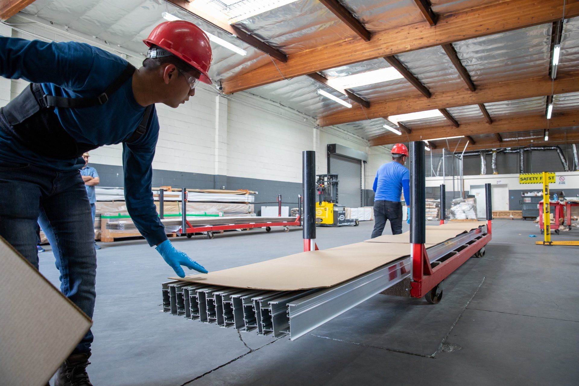 Two men loading a cart up with long pieces of metal