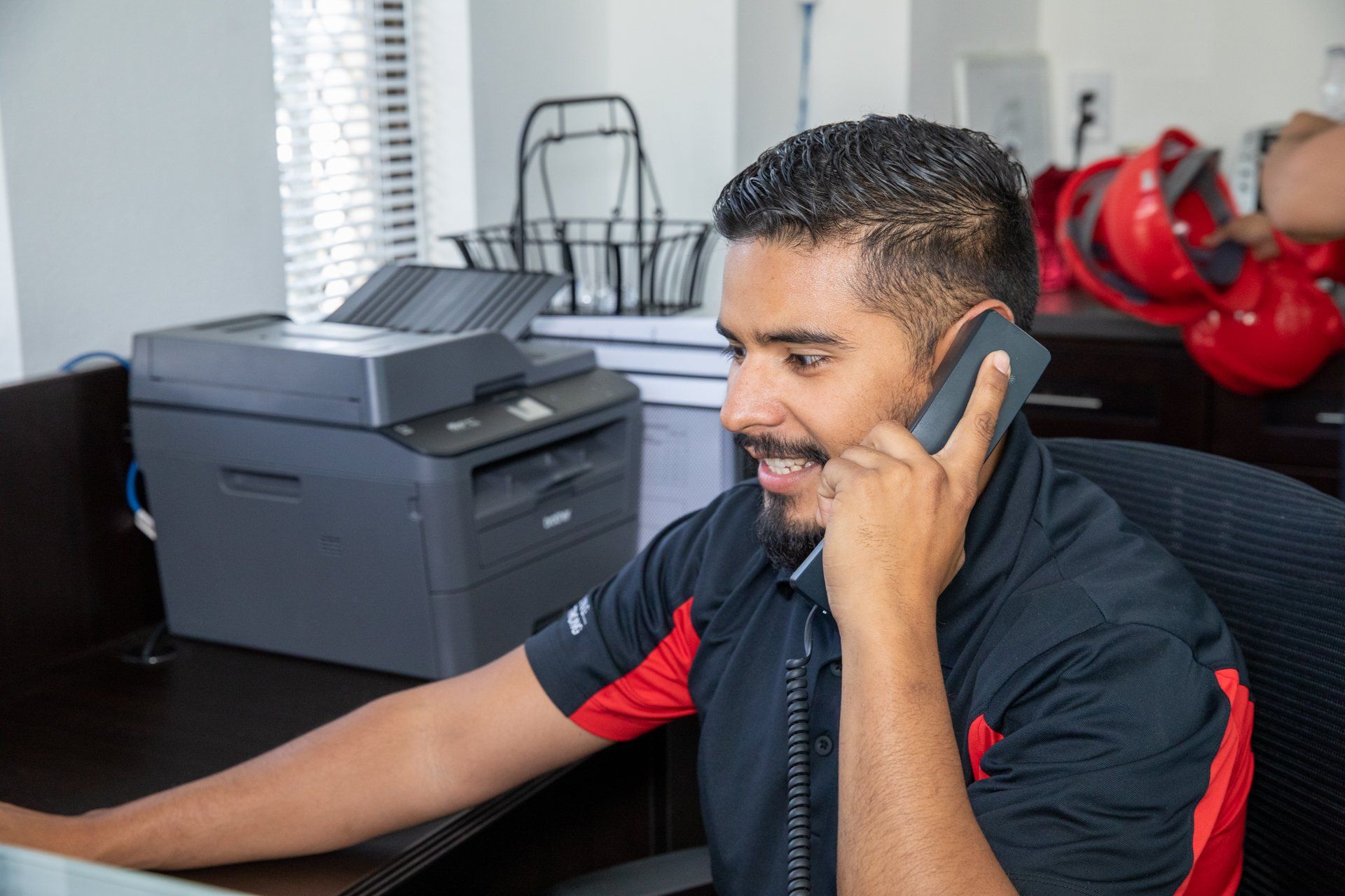 man in polo shirt answering phone at front desk