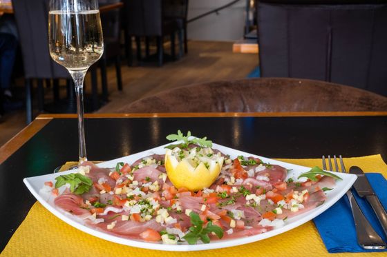 Une assiette de carpaccio de poisson et son demi-citron