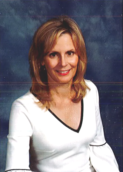 Portrait of a smiling woman in a white top against a blue studio backdrop