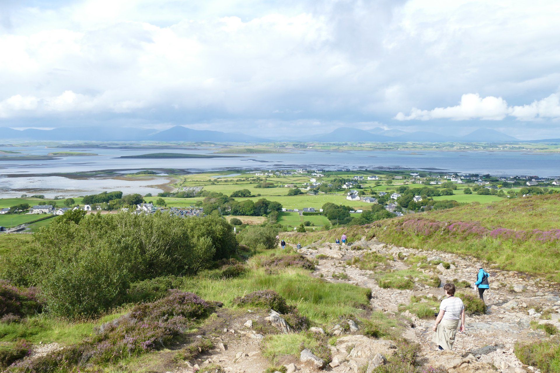 A group of people are walking up a hill with a view of the sea
