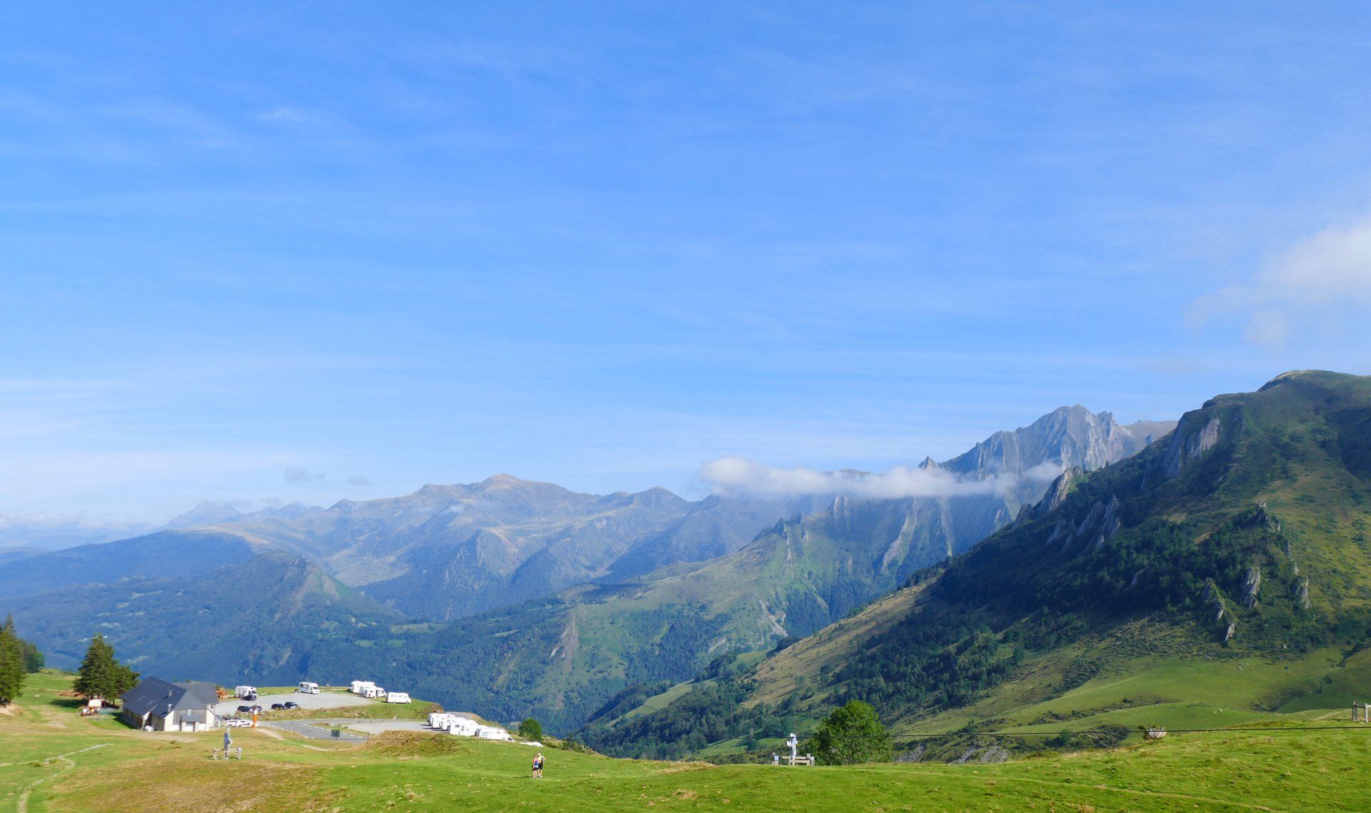 A grassy hillside with mountains in the background and a blue sky in France