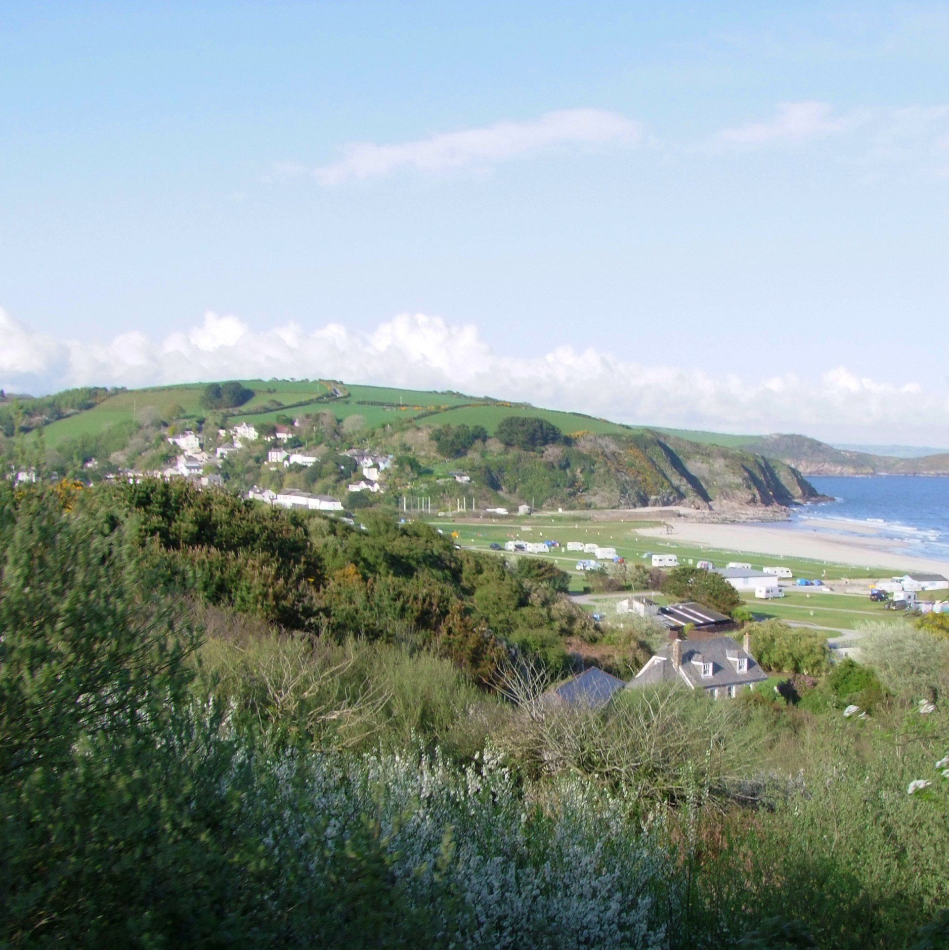 A view of a campsite in Cornwall with a beach in the background
