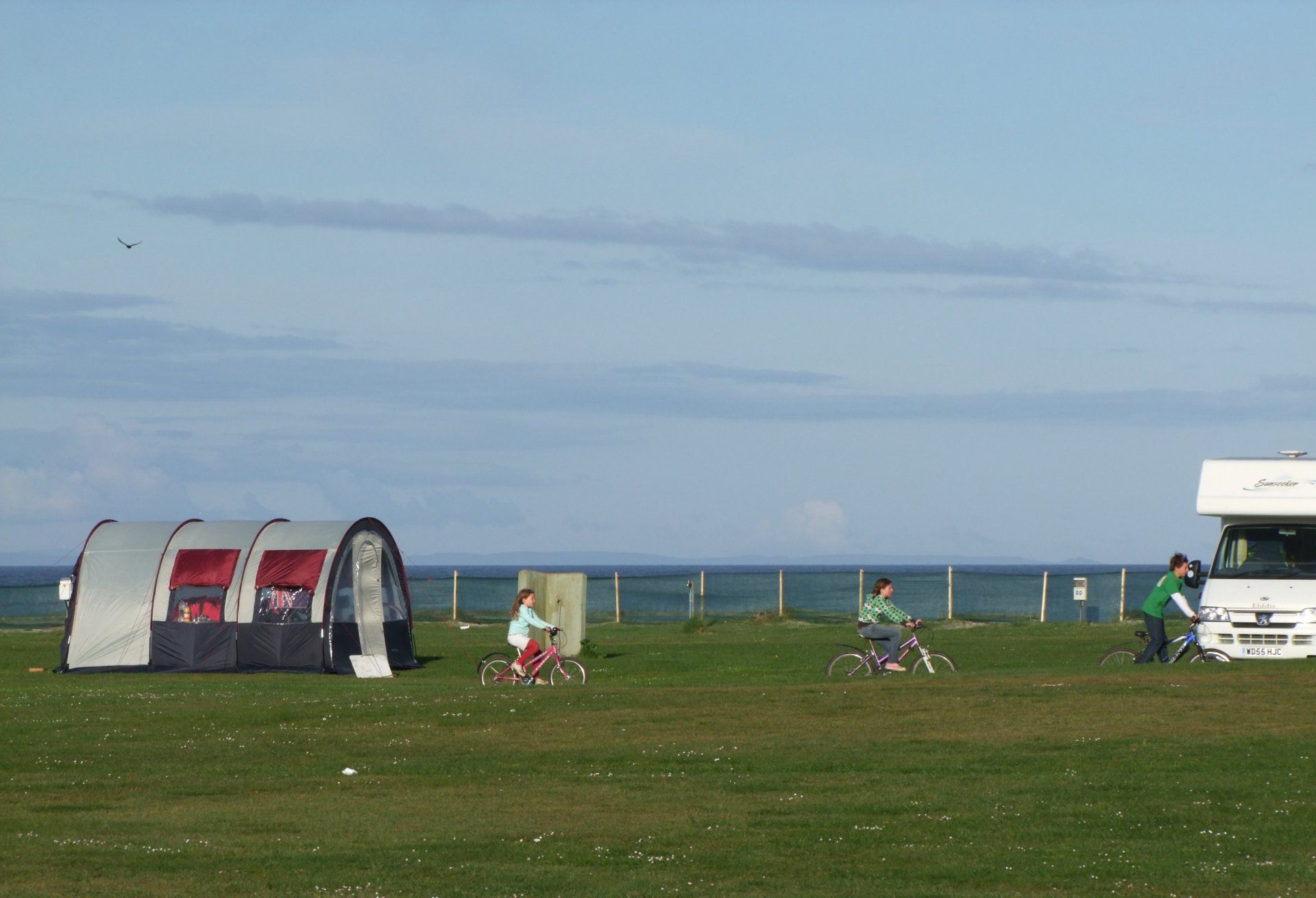 A rv is parked in a grassy field next to a tent