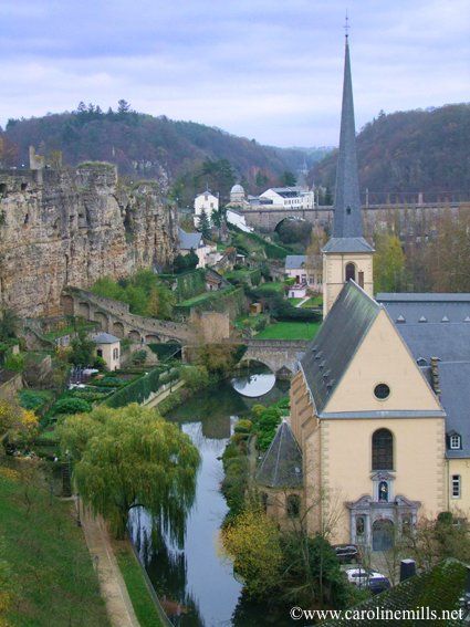 A church in Luxembourg with a steeple sits next to a river