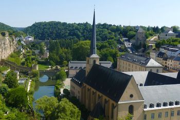 An aerial view of a church in Luxembourg surrounded by trees and a river