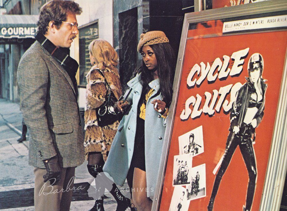 Scene from Owl and the Pussycat with George Segal looking at Cycle Sluts movie poster.