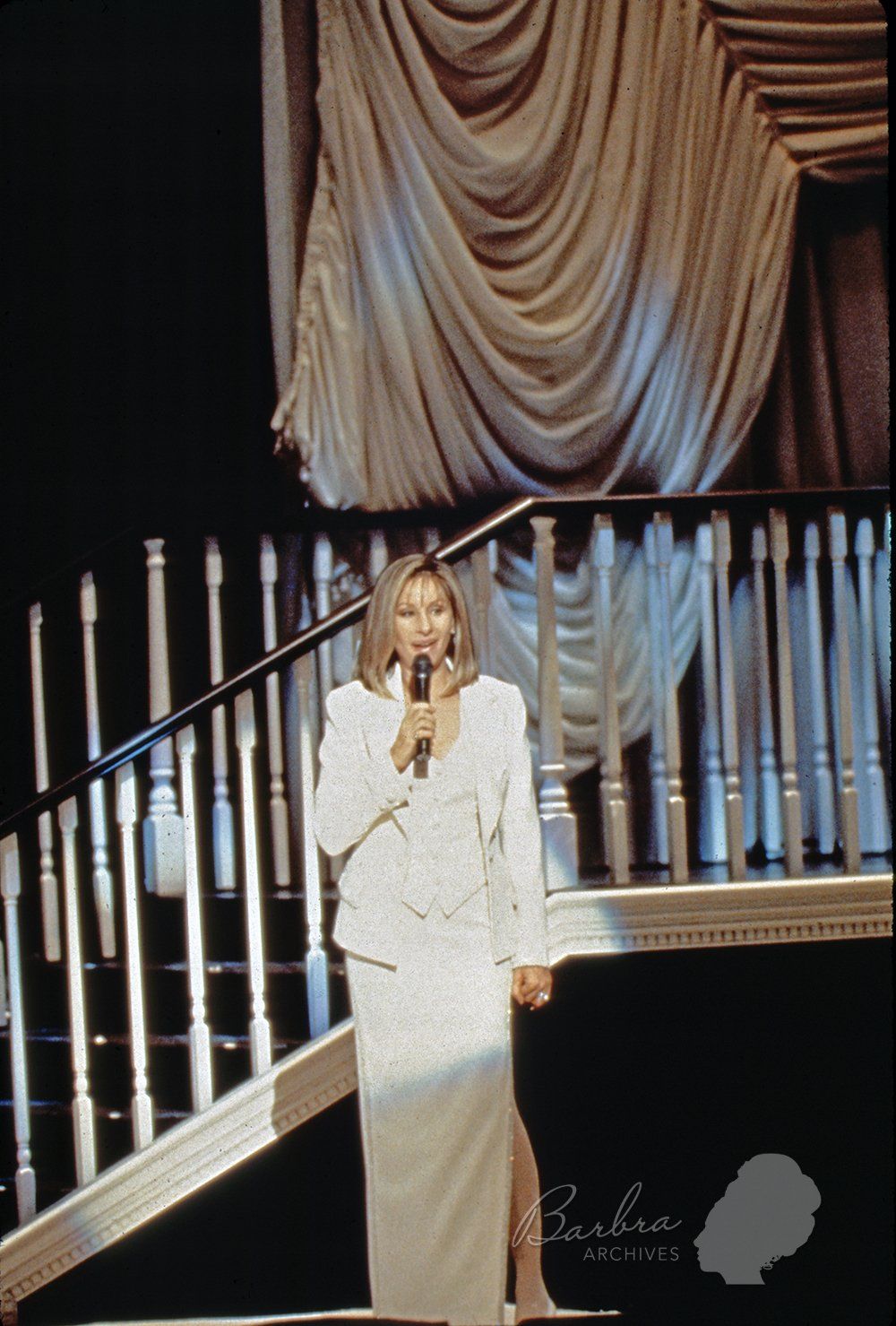 Barbra Streisand wearing off-white suit and skirt in the second act of her concert. Barbra Streisand wearing off-white suit and skirt in the second act of her concert.