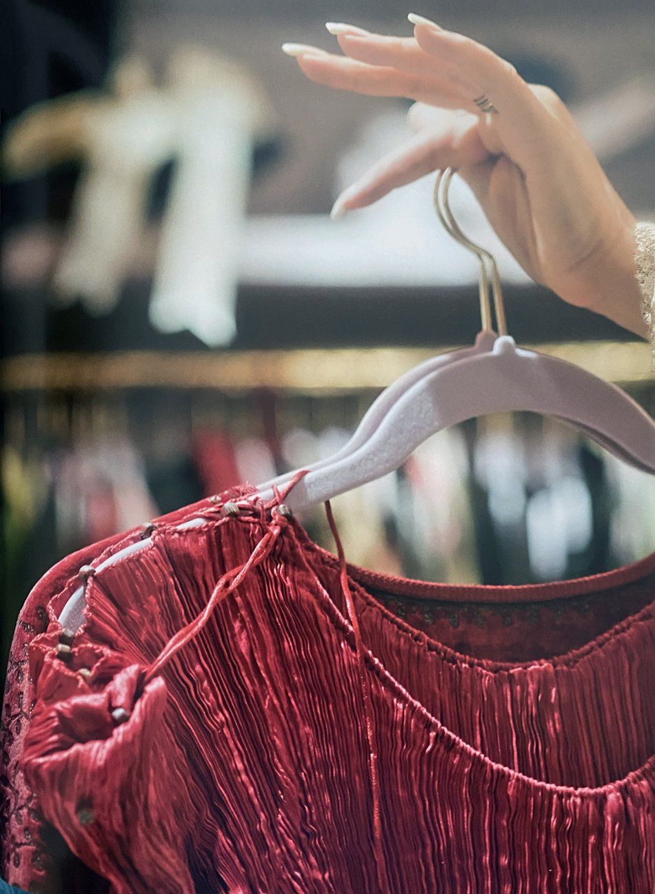 Streisand's hands shown holding up the Fortuny dress on a hanger.