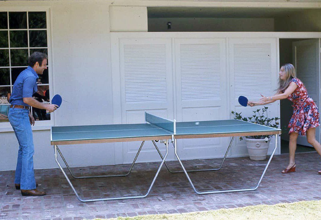 Candid photo of James Caan and Barbra taking a break from filming and playing a game of ping pong.