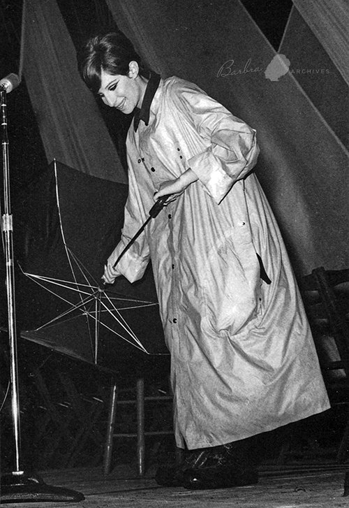 Barbra Streisand in concert in Atlanta holding an umbrella because of the rain.