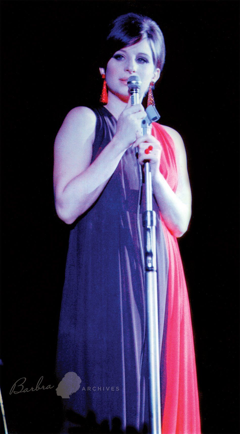Streisand at mic wearing black sparkly dress.