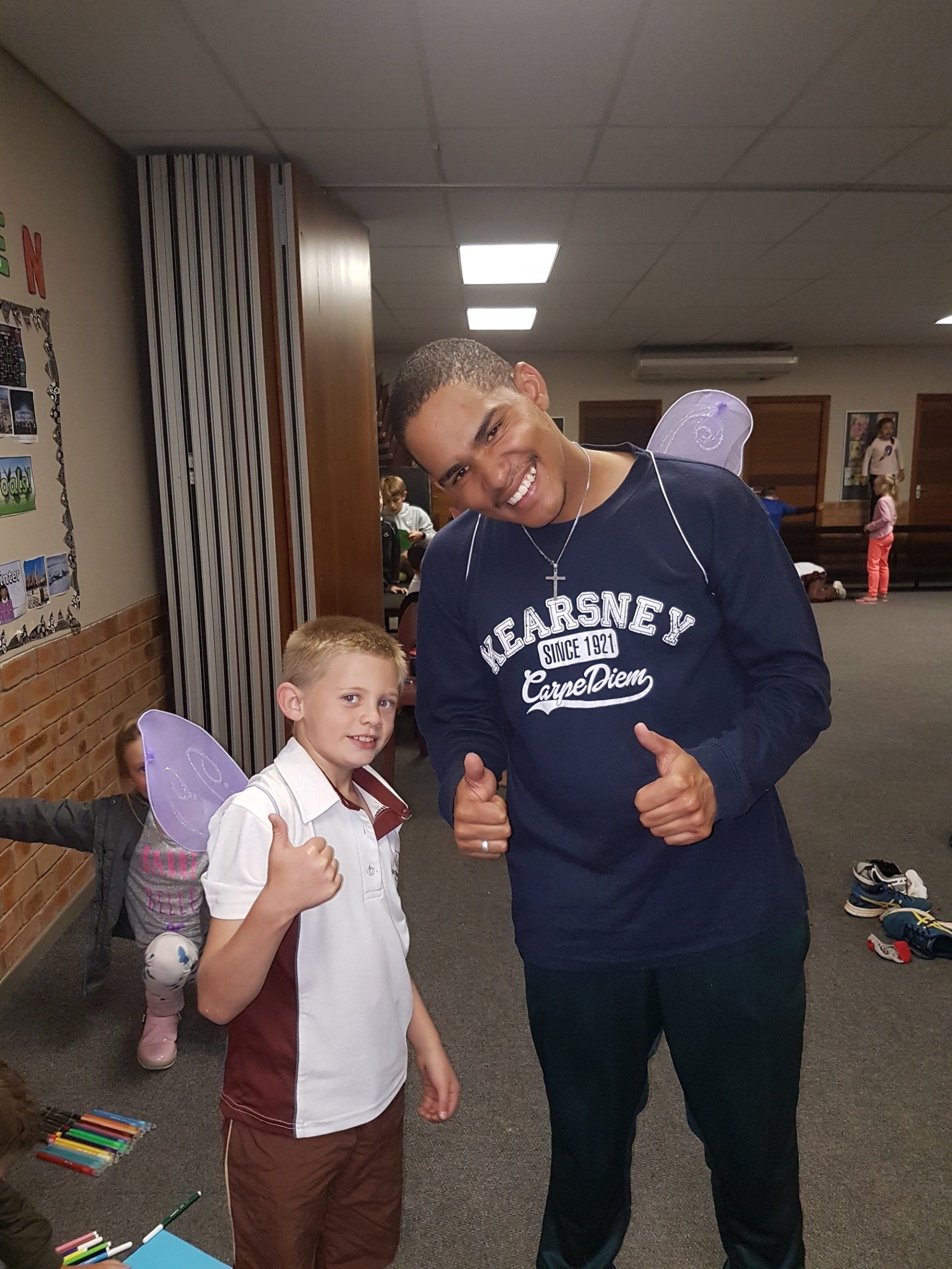 A man and a boy are posing for a picture and the boy is wearing a shirt that says earsney