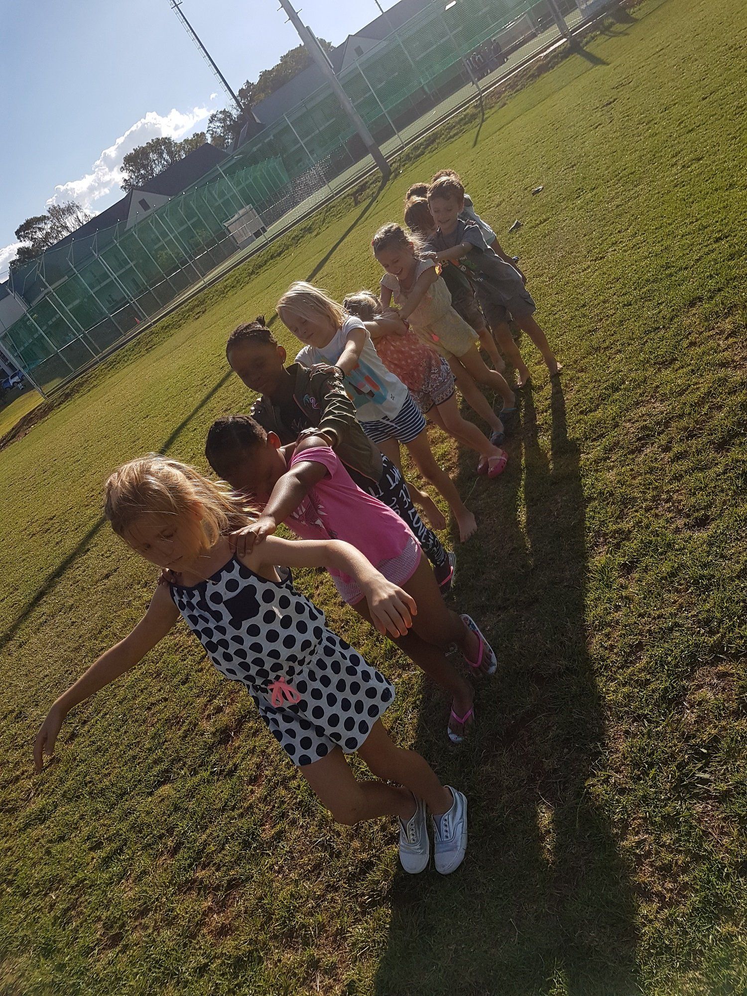 A group of children are standing in a row on a lush green field.