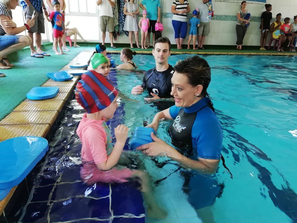 A woman is teaching a child how to swim in a pool