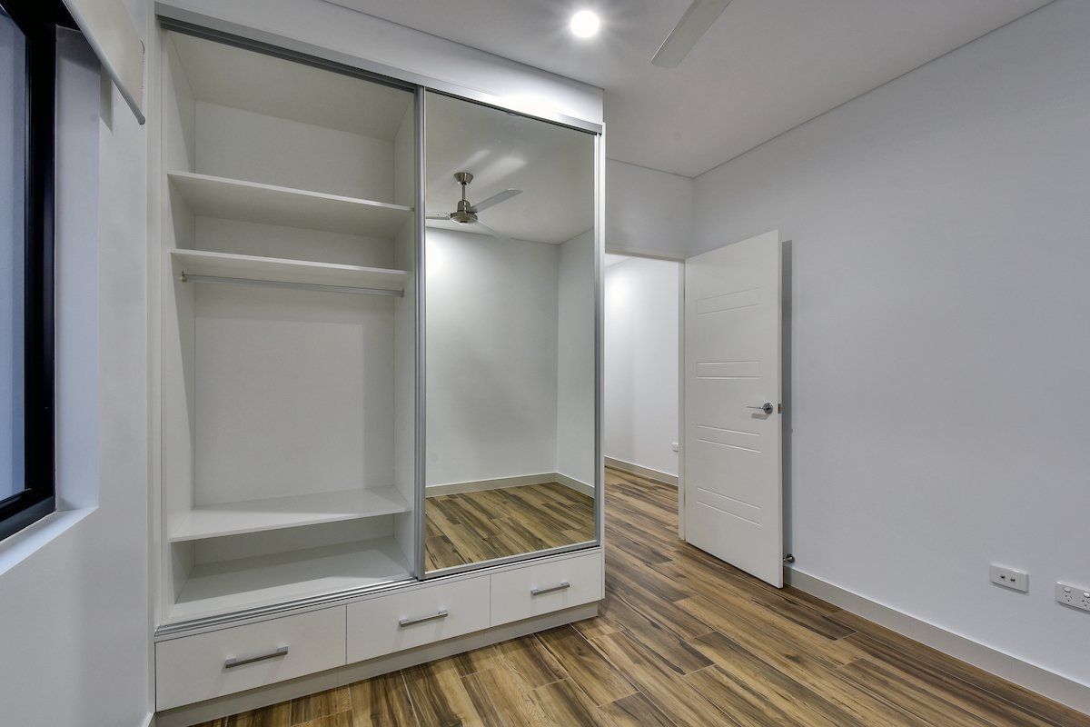 An empty bedroom with a sliding wardrobe and a mirrored door.