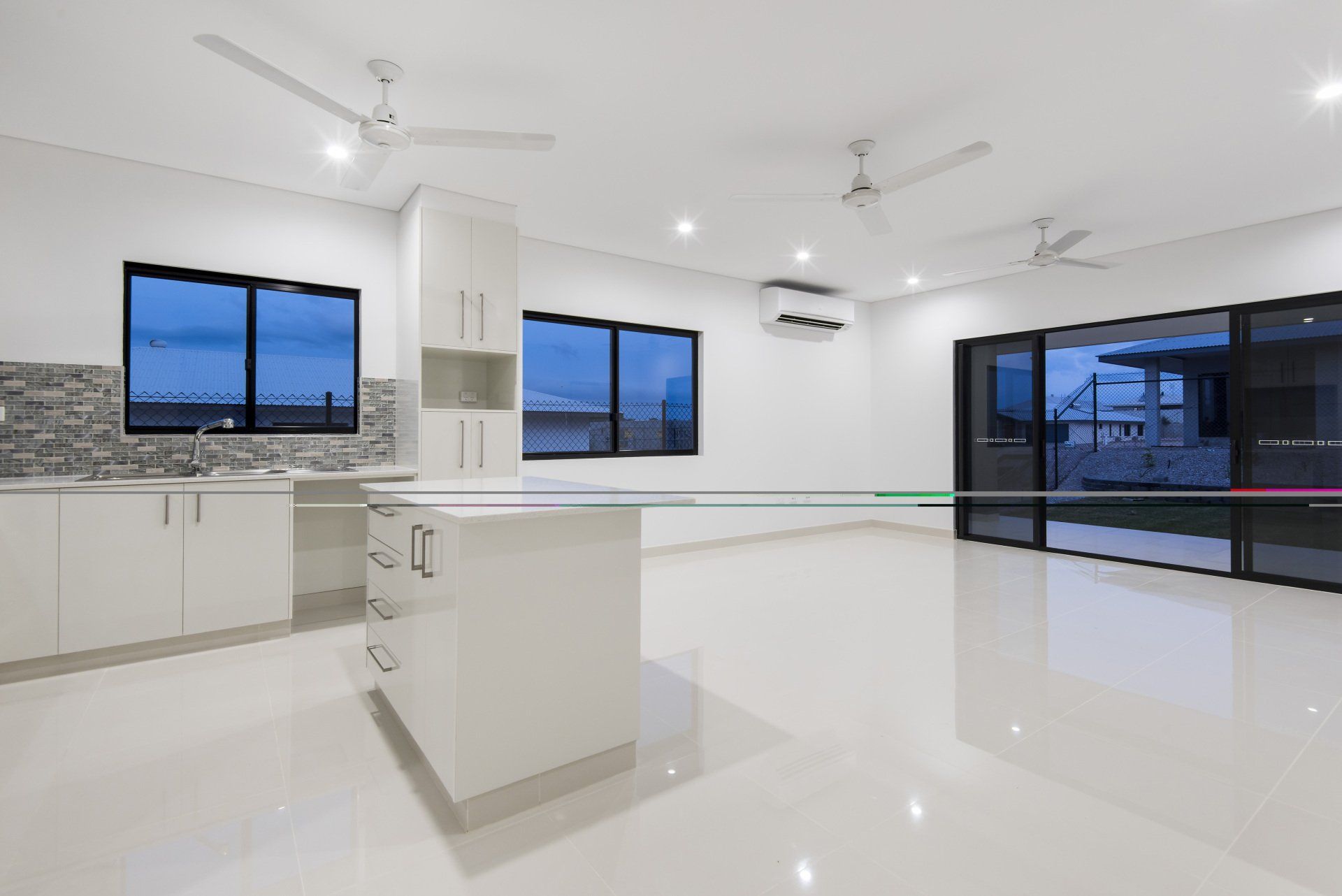 An empty kitchen with white cabinets and a ceiling fan.