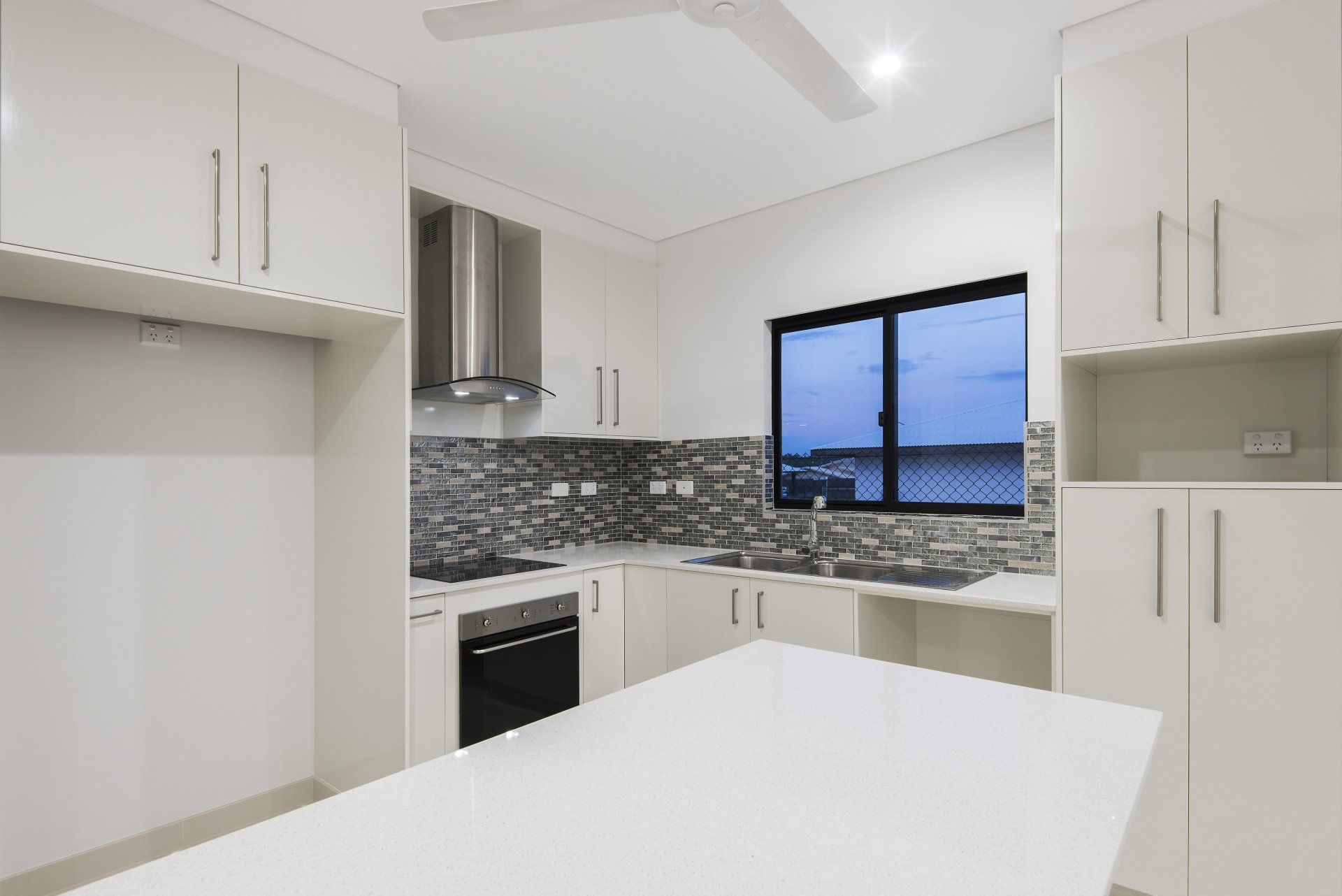 A kitchen with white cabinets , stainless steel appliances , and a large island.