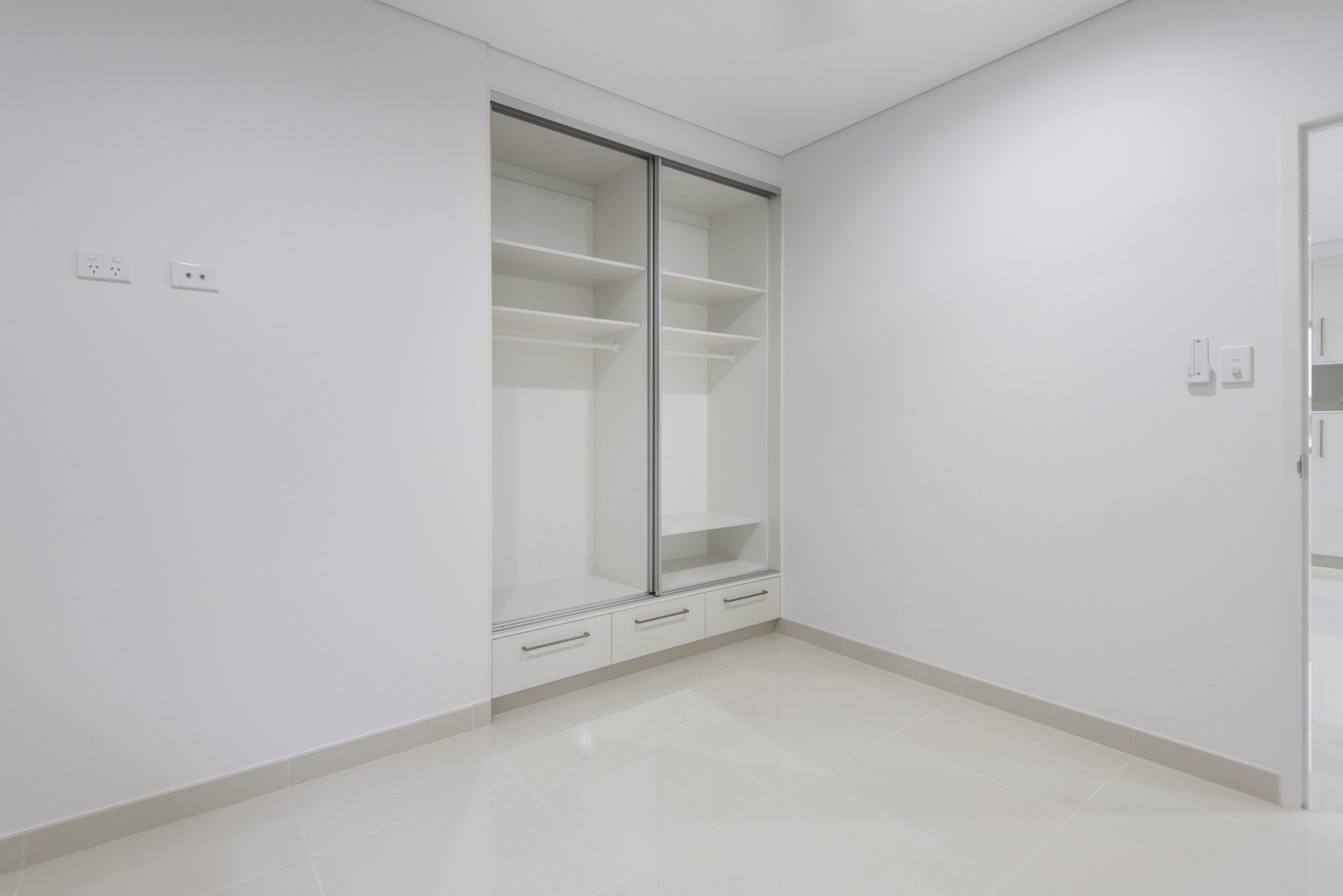 An empty room with white walls and sliding doors.