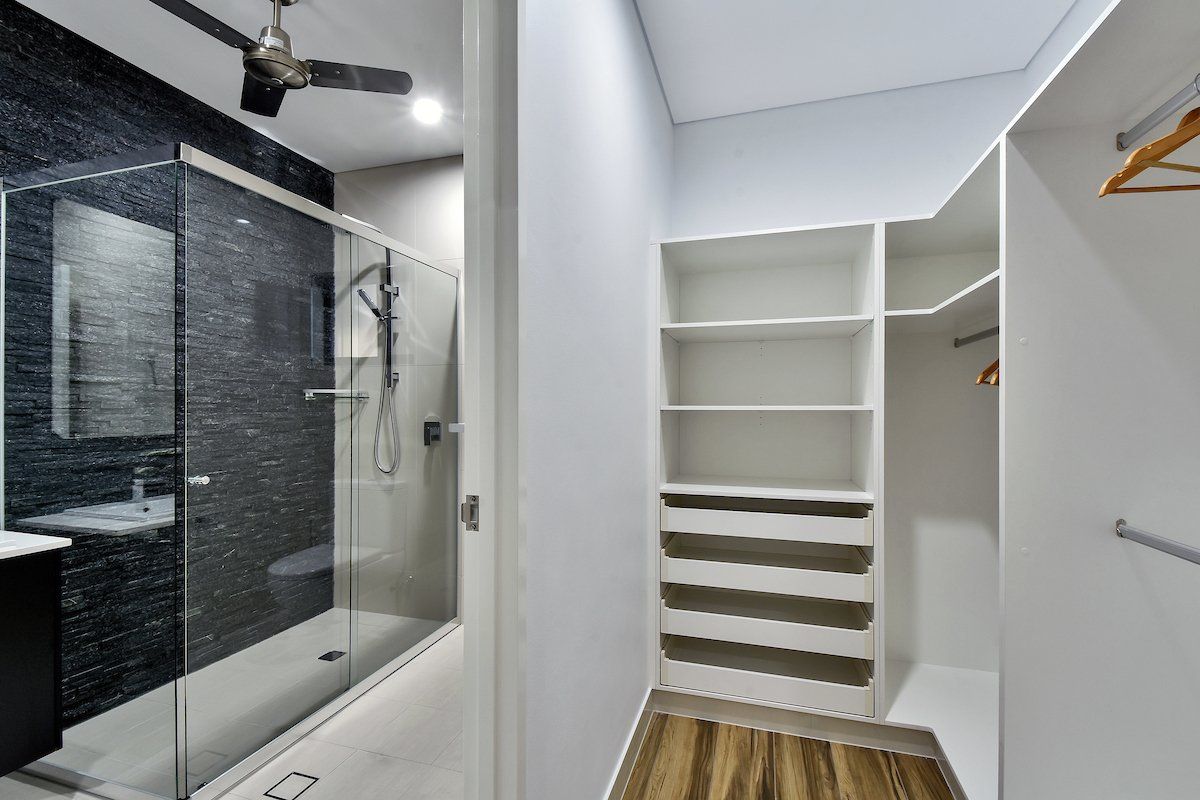 A walk in closet in a bathroom with a walk in shower.