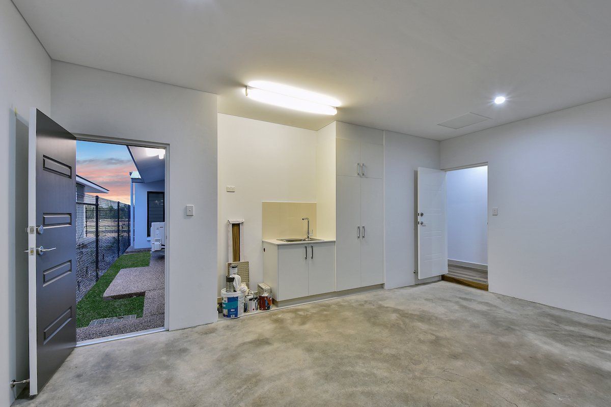 An empty garage with a sink and cabinets in it.