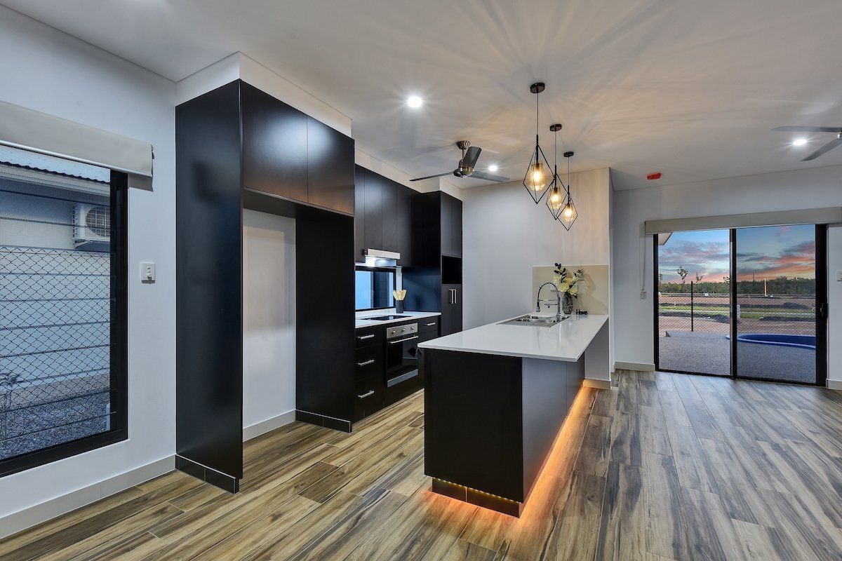 A kitchen with black cabinets and a large island in the middle of the room.