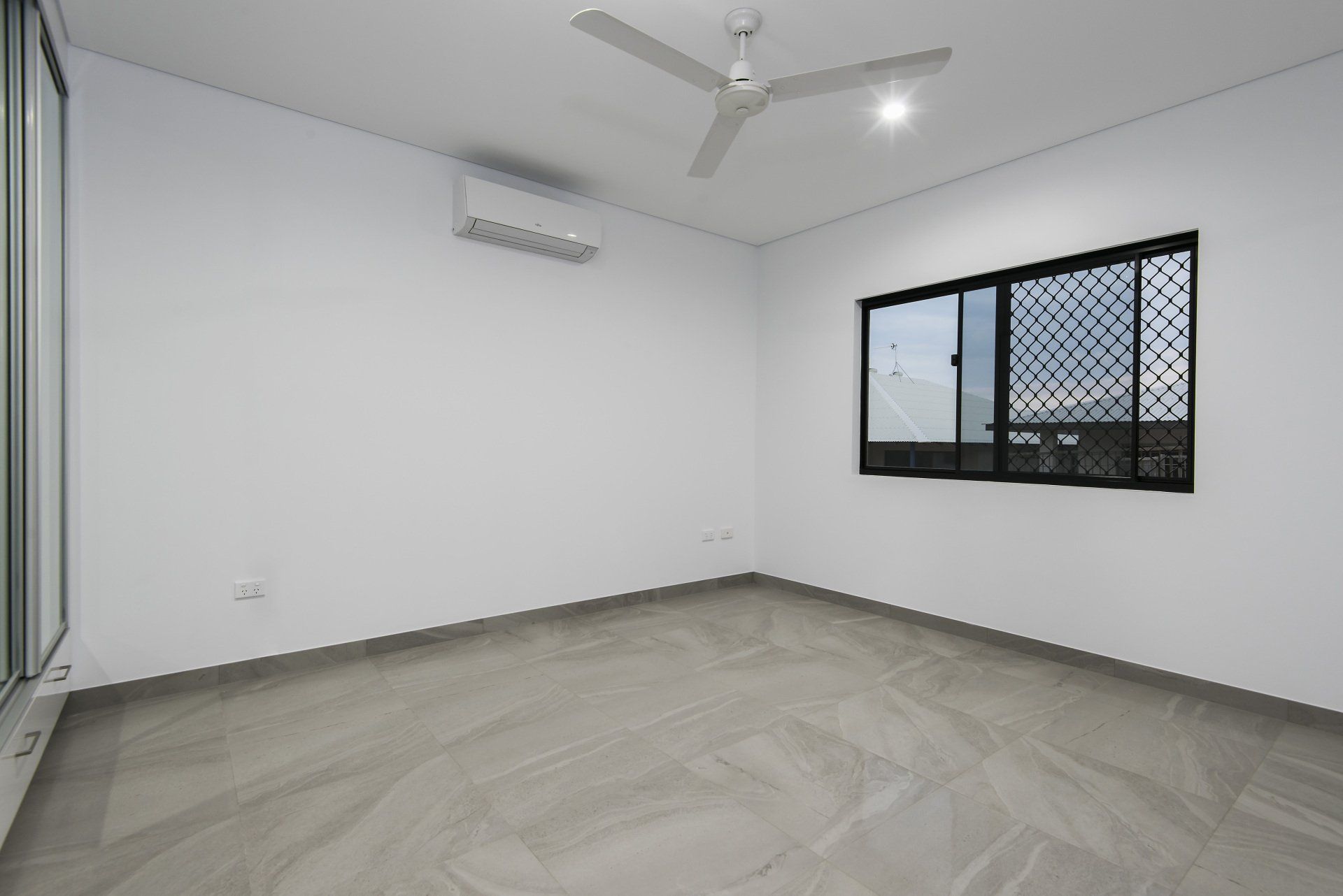 An empty room with a ceiling fan and a window.